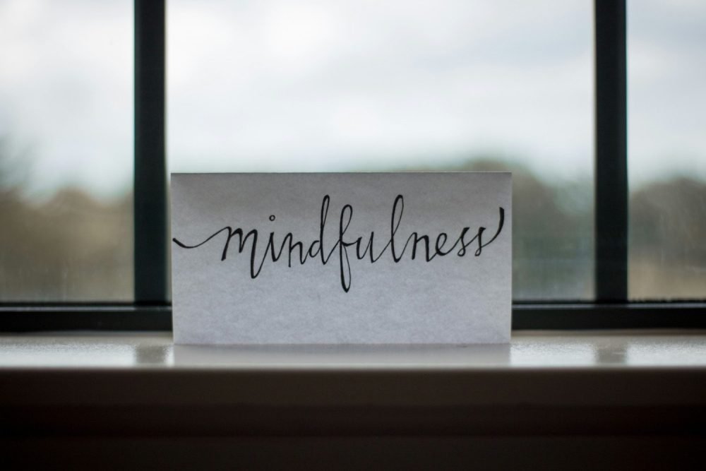 Sewing and mindfulness go hand in hand - image of paper on a windowsill with the word "mindfulness" written in caligraphy