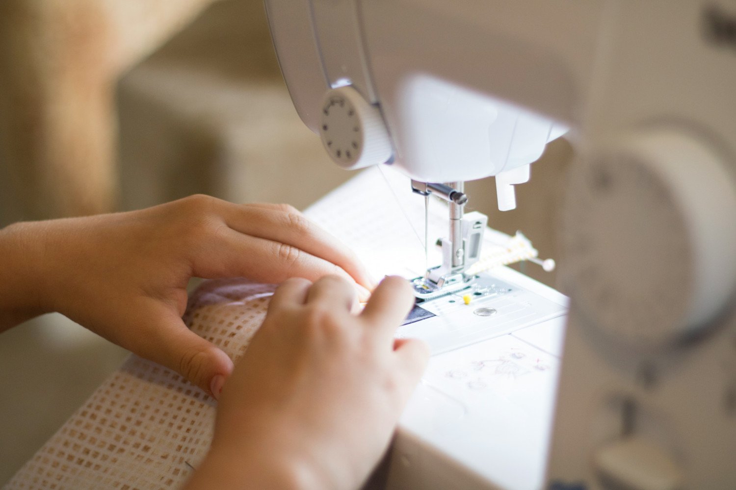 If sewing feels intimidating, start small and pick simple projects - close up image of hands using a sewing machine.